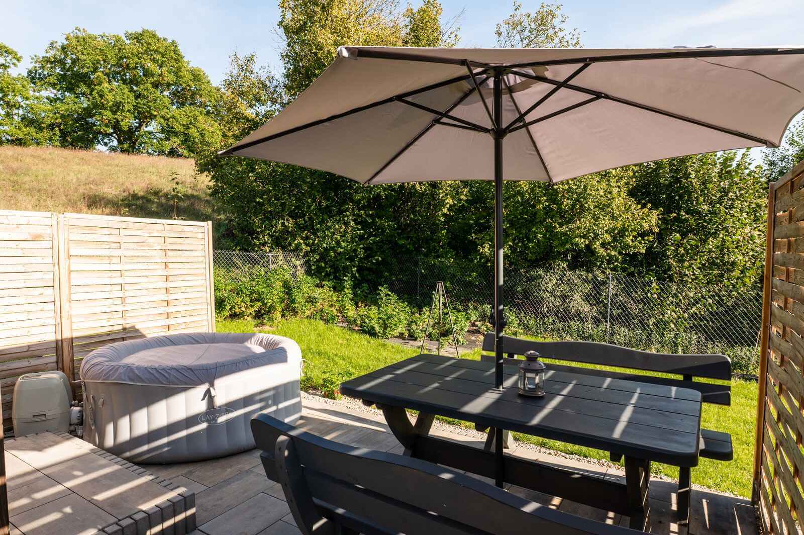 Prywatne jacuzzi, stół i parasol na tarasie domku